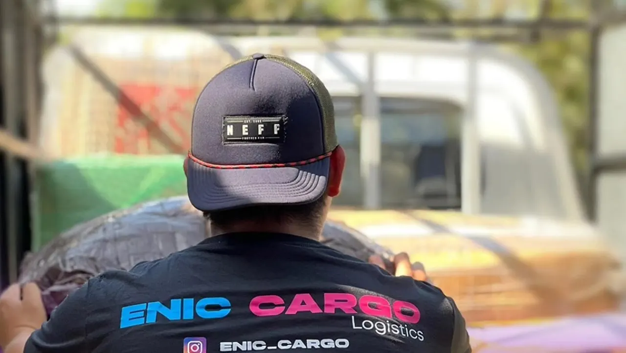 Trabajador de ENIC Cargo con camiseta de la empresa cargando encomiendas en un camión